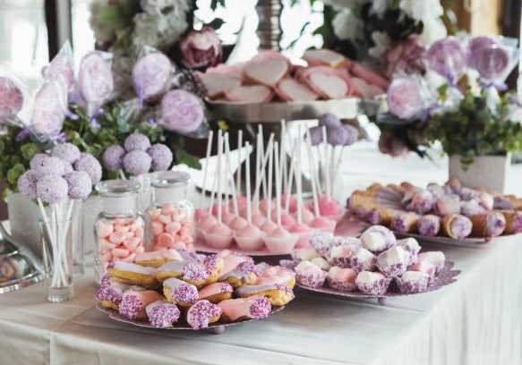 Pink candy bar for holiday celebration. Sweet buffet for birthday party or wedding. Desserts assortment against wooden background, catering concept